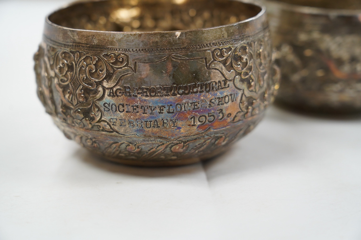 A pair of mid 20th century Indian embossed white metal small bowls, inscribed ' Agri-Horticultural Society Flower Show February 1953', diameter 10.4cm, together with a similar box and cover. Condition - poor to fair